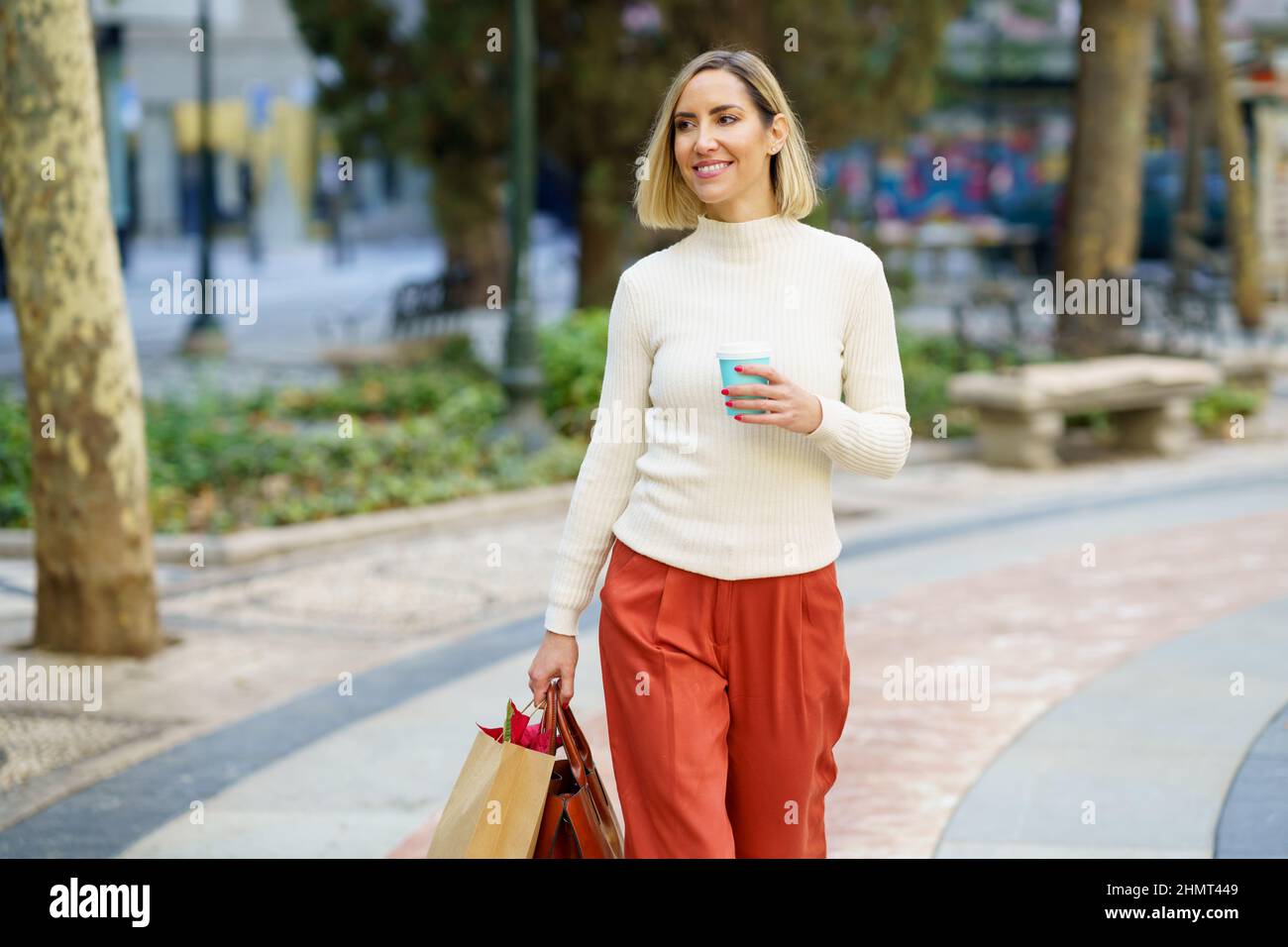Femme souriante avec sac en papier à emporter pour le café Banque D'Images