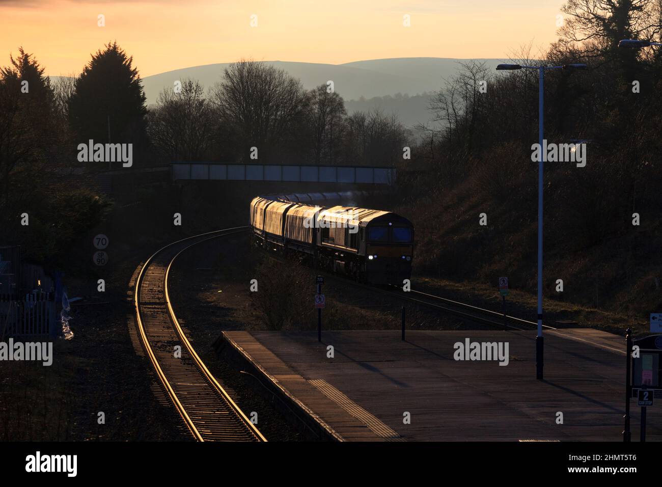 Locomotive diesel de classe 66 de fret ferroviaire de GB passant par Chinley, vallée de l'espoir, Derbyshire avec un train de fret de wagons vides au coucher du soleil Banque D'Images