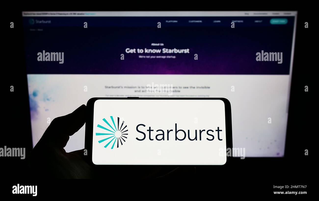 Personne tenant un smartphone avec le logo de la société logicielle américaine Starburst Data Inc. À l'écran devant le site Web. Mise au point sur l'affichage du téléphone. Banque D'Images