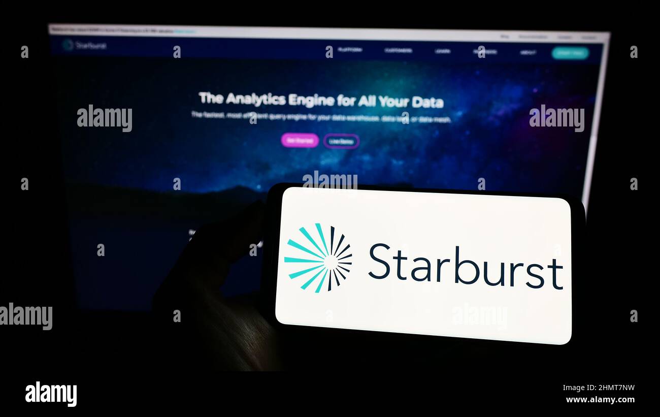 Personne tenant un téléphone portable avec le logo de la société américaine de logiciel Starburst Data Inc. À l'écran devant la page Web. Mise au point sur l'affichage du téléphone. Banque D'Images