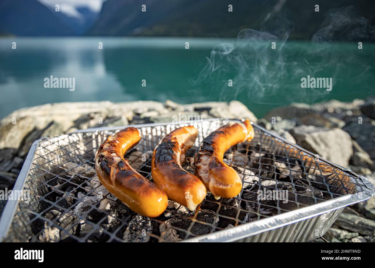 Griller les saucisses sur la grille du barbecue à usage unique. Belle Nature Norvège paysage naturel. Banque D'Images