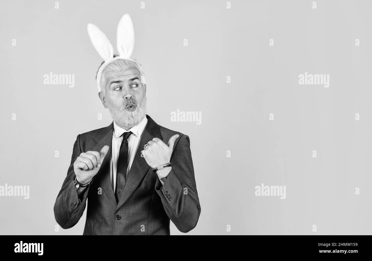 Dimanche de Pâques. Heureux homme d'affaires annonçant le produit. Homme barbu avec des oreilles de lapin pointant. Présentation du produit. Promotion produit. Promotion et Banque D'Images