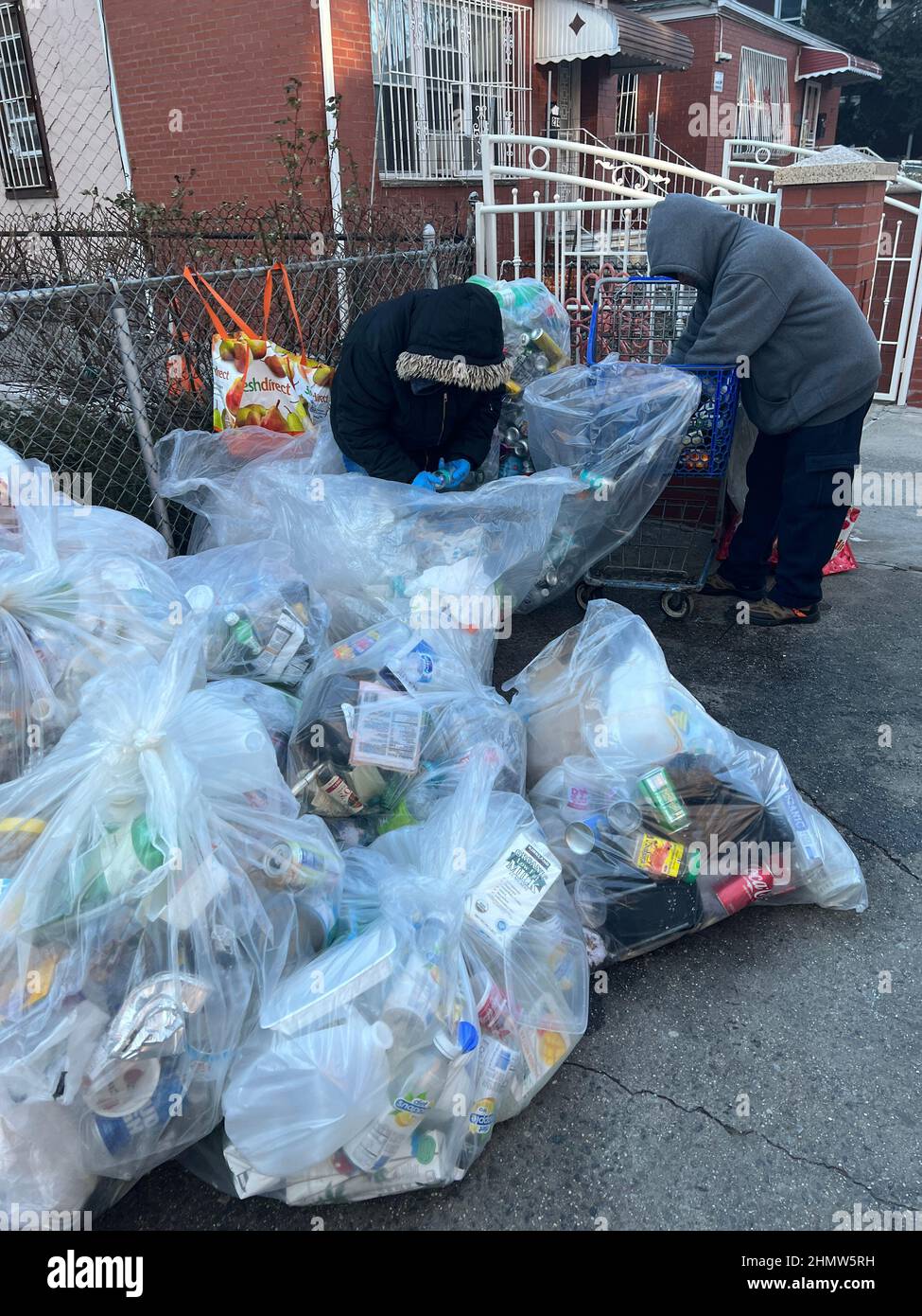 Le éliminateur triant les bouteilles en aluminium et en plastique des ordures recyclables dans la rue pour les ramasser à Brooklyn, New York. Banque D'Images