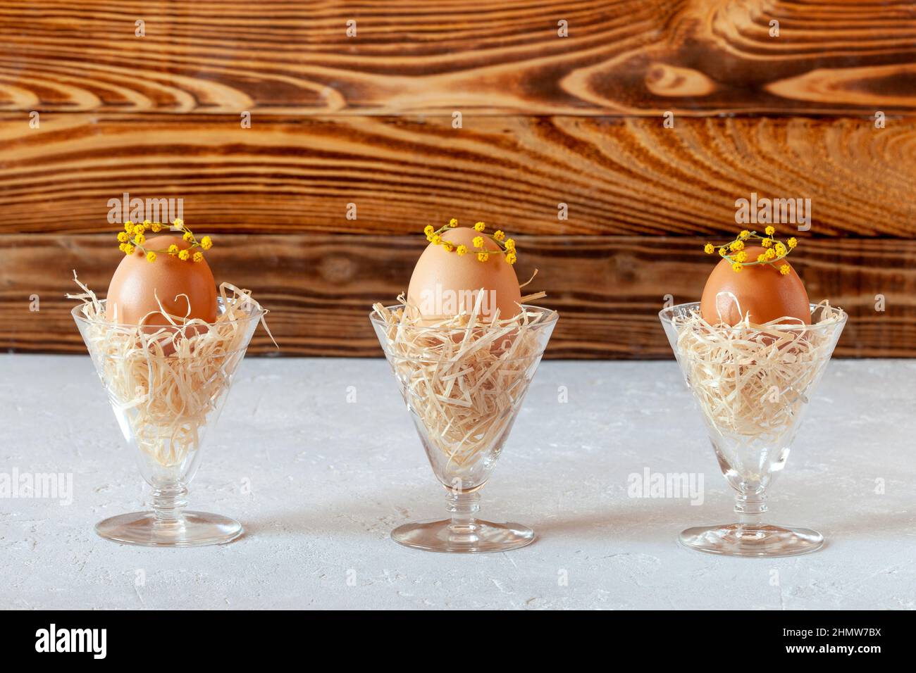 Mimosa a décoré des oeufs dans les nids en verres de cristal, idée de décoration de Pâques Banque D'Images