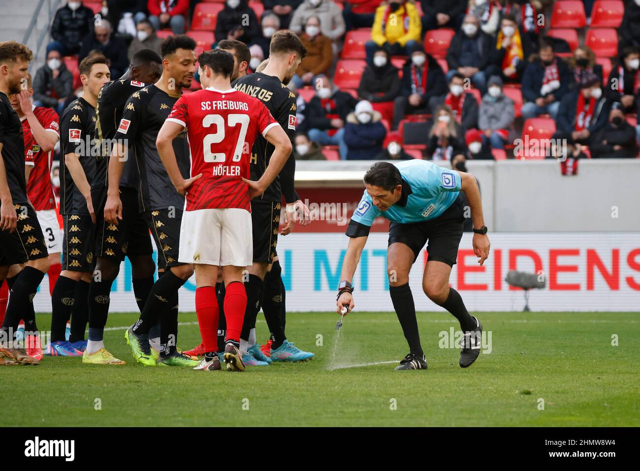 Allemagne. 12th févr. 2022. Freiburg im Breisgau, Allemagne. 12th févr. 2022. Football: Bundesliga, SC Freiburg - FSV Mainz 05, Matchday 22, Europa-Park Stadion: #Arbitre Denis Aytekin pulvérise un coup de pied gratuit sur le terrain tandis que les joueurs de SC Freiburg et FSV Mainz 05 se tiennent à côté. Credit: Philipp von Ditfurth/dpa - NOTE IMPORTANTE: Conformément aux exigences du DFL Deutsche Fußball Liga et du DFB Deutscher Fußball-Bund, il est interdit d'utiliser ou d'avoir utilisé des photographies prises dans le stade et/ou du match sous forme de séquences et/ou de séries de photos de type vidéo./dpa/Alamy Banque D'Images