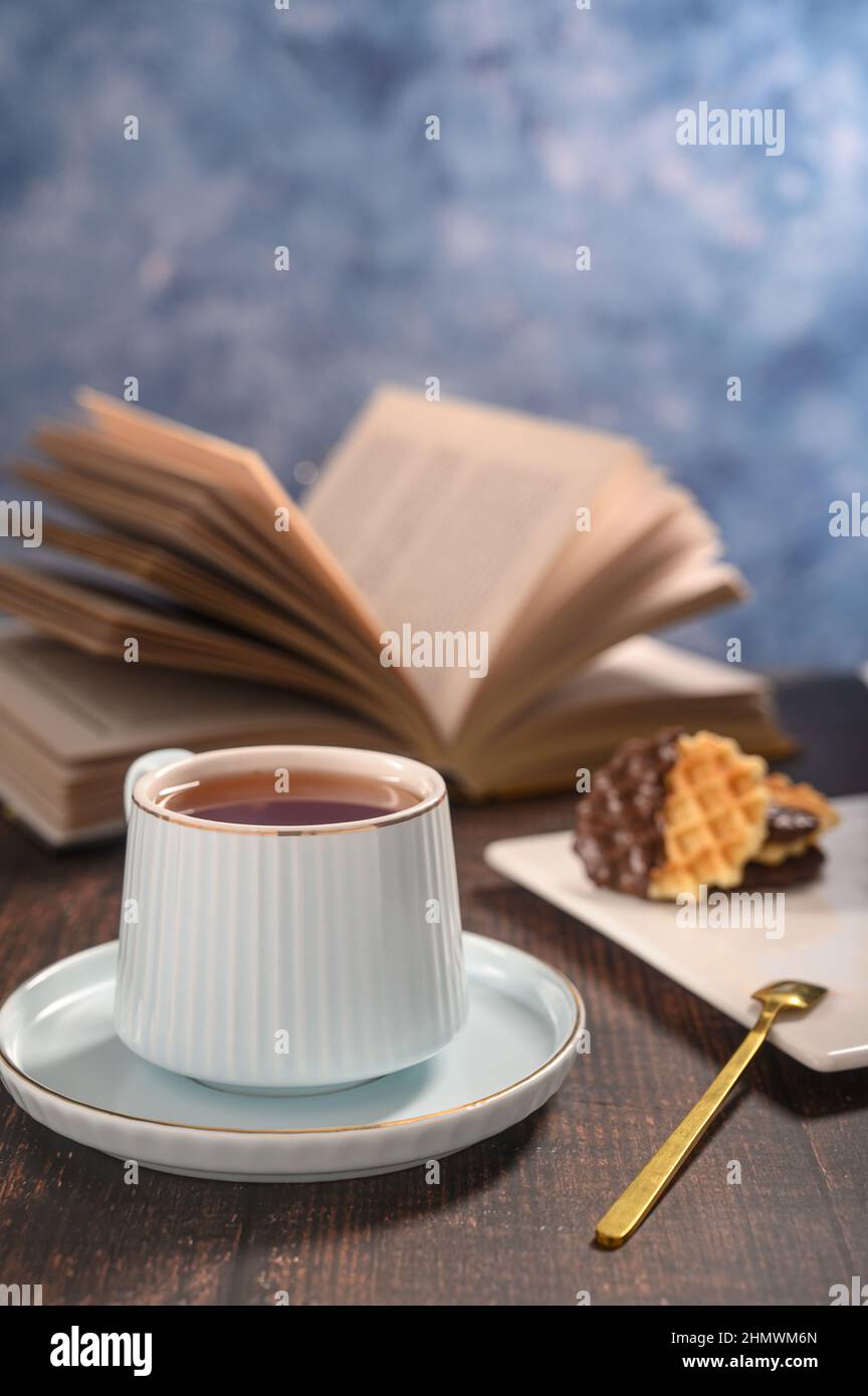 Une grande photo de la relaxation matinale se fait dans des couleurs chaudes. Une tasse de thé et un livre est le meilleur début de journée. Une ambiance romantique vous permettra d'améliorer votre atmosphère Banque D'Images