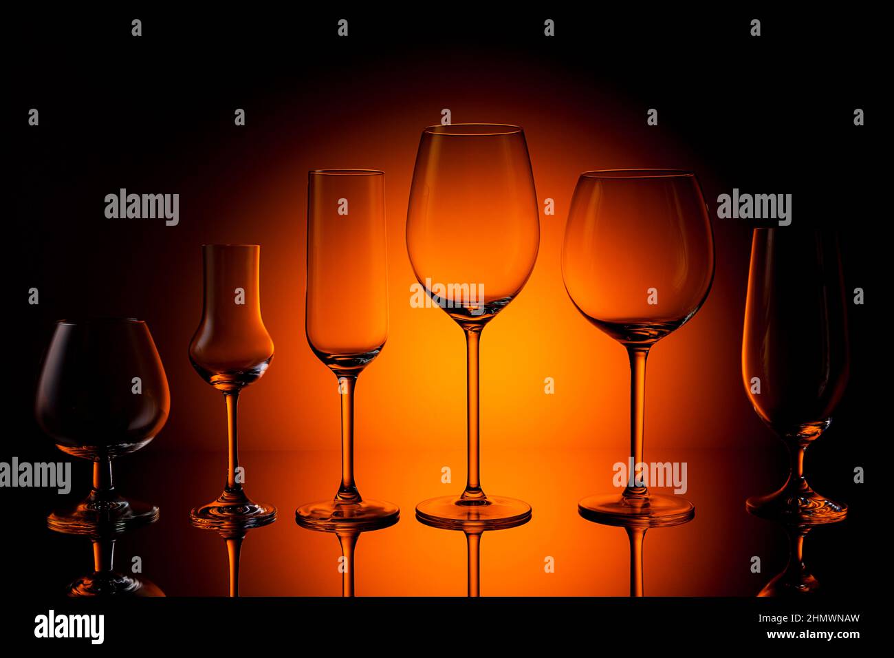 Une rangée de différents verres de vin, de whisky, de grappa, de champagne et de bière sur fond de coucher de soleil orange. Prise en Studio avec un 5D Mark III Banque D'Images