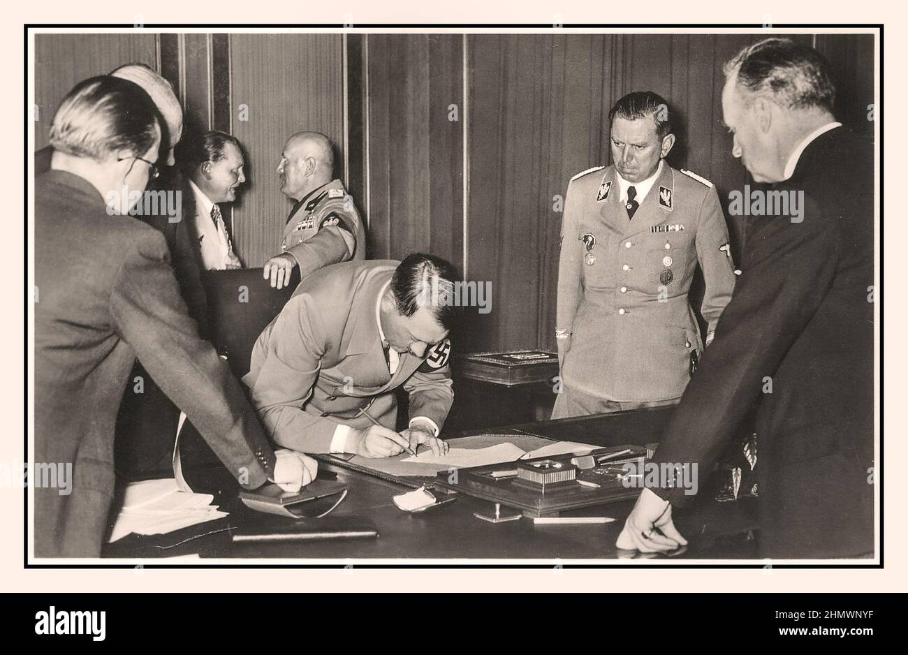 1938, Adolf Hitler signant l'Accord de Munich 30th septembre 1938 'Hitler signe l'Accord de Munich', en arrière-plan le chef du faciste italien Mussolini et Goering chef de la Luftwaffe allemande en conversation l'Accord de Munich était un accord conclu à Munich le 30 septembre 1938, par l'Allemagne, le Royaume-Uni, la France, Et en Italie. Il a fourni "la cession à l'Allemagne du territoire allemand de Sudeten" de la Tchécoslovaquie, Banque D'Images