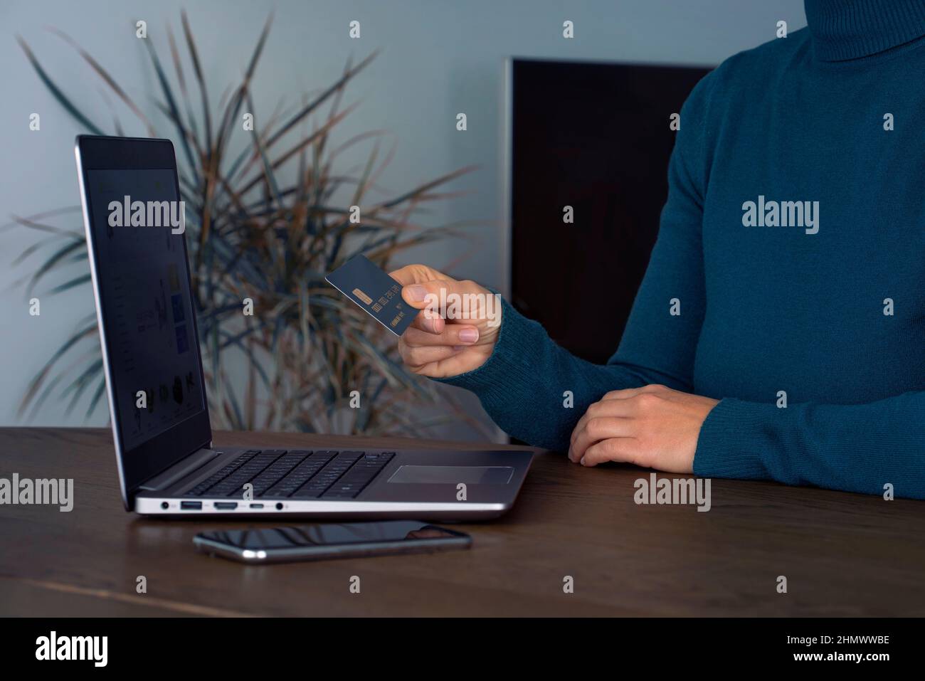 Jeune femme tenant une carte de crédit bancaire et utilisant un ordinateur portable pour acheter sur Internet, concept d'achat en ligne à la maison Banque D'Images