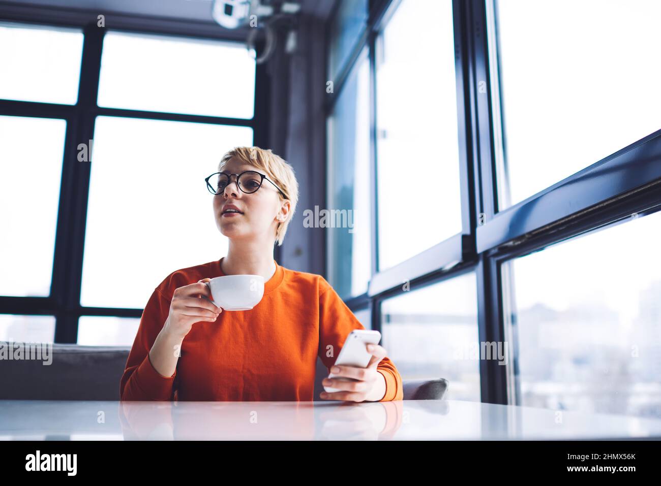 Jeune femme prenant un café avec un smartphone Banque D'Images