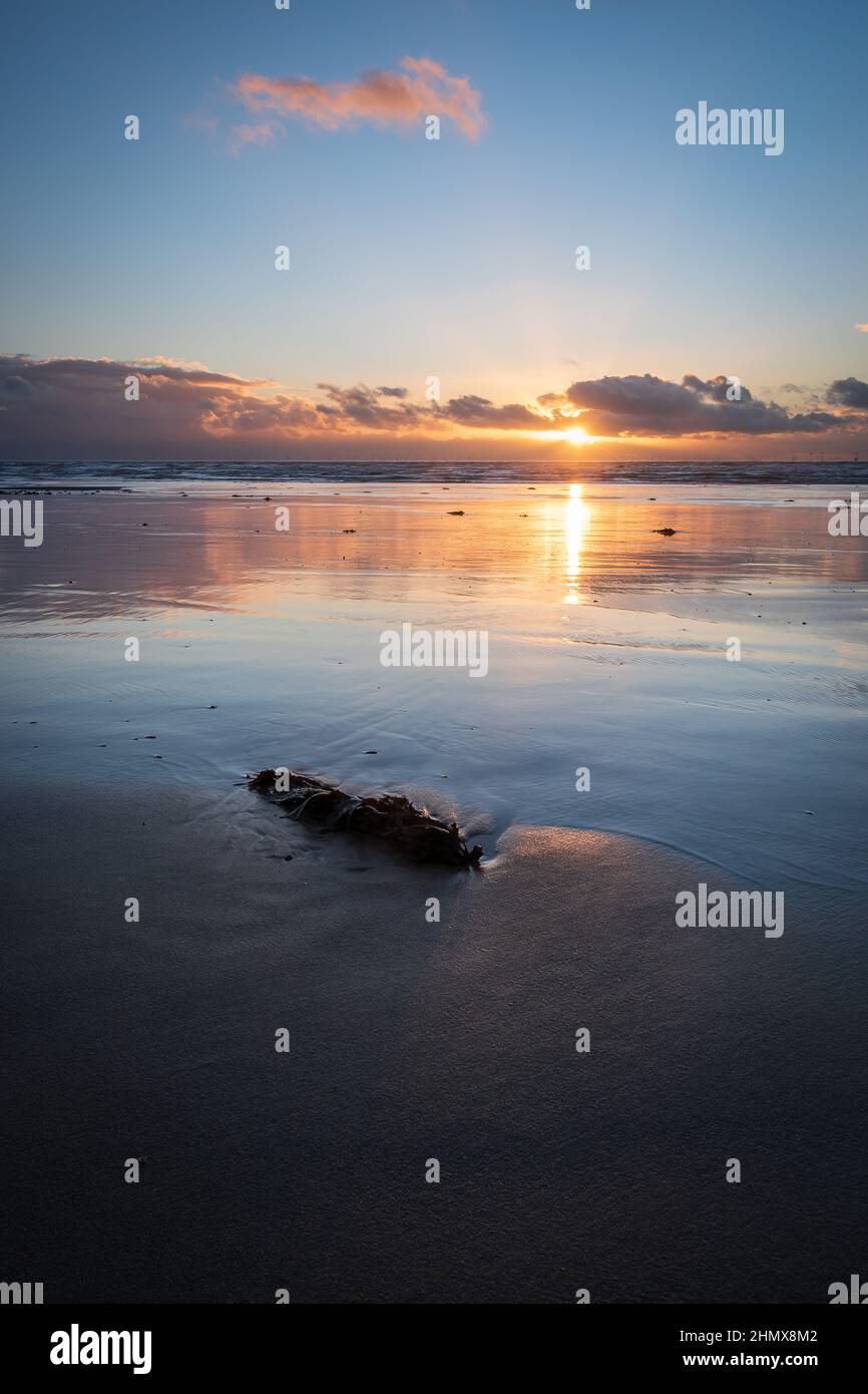 Coucher de soleil avec nuages et réflexions illuminés, à Sandy Gap, plage de Walney, île de Walney, barrow in furness, Cumbria, Royaume-Uni, le 4th février 2022 Banque D'Images