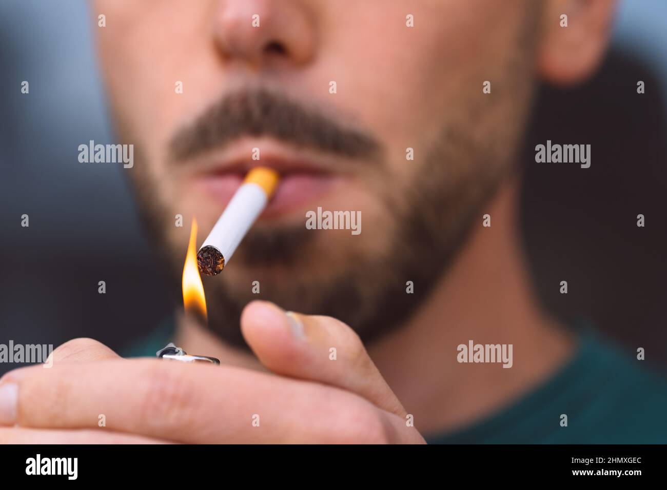 Gros plan de jeune homme éclairant la cigarette avec l'allume-cigare. Tabagisme et dépendance à la nicotine Banque D'Images