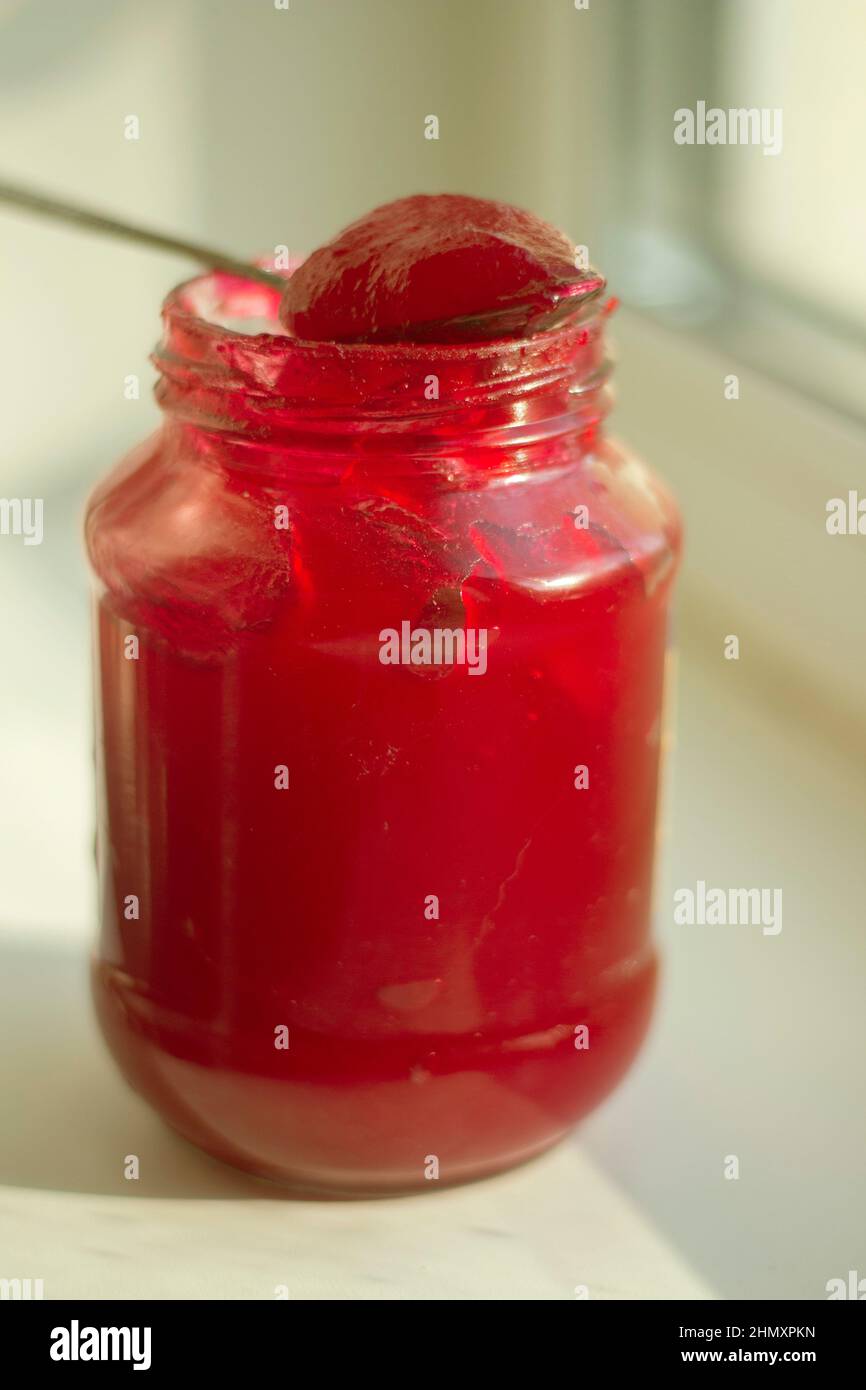 Bourrage dans le bol. Baie rouge dans le sucre. Confiture à la lumière naturelle. Pot en verre avec baies confites. Mets sucrés. Banque D'Images