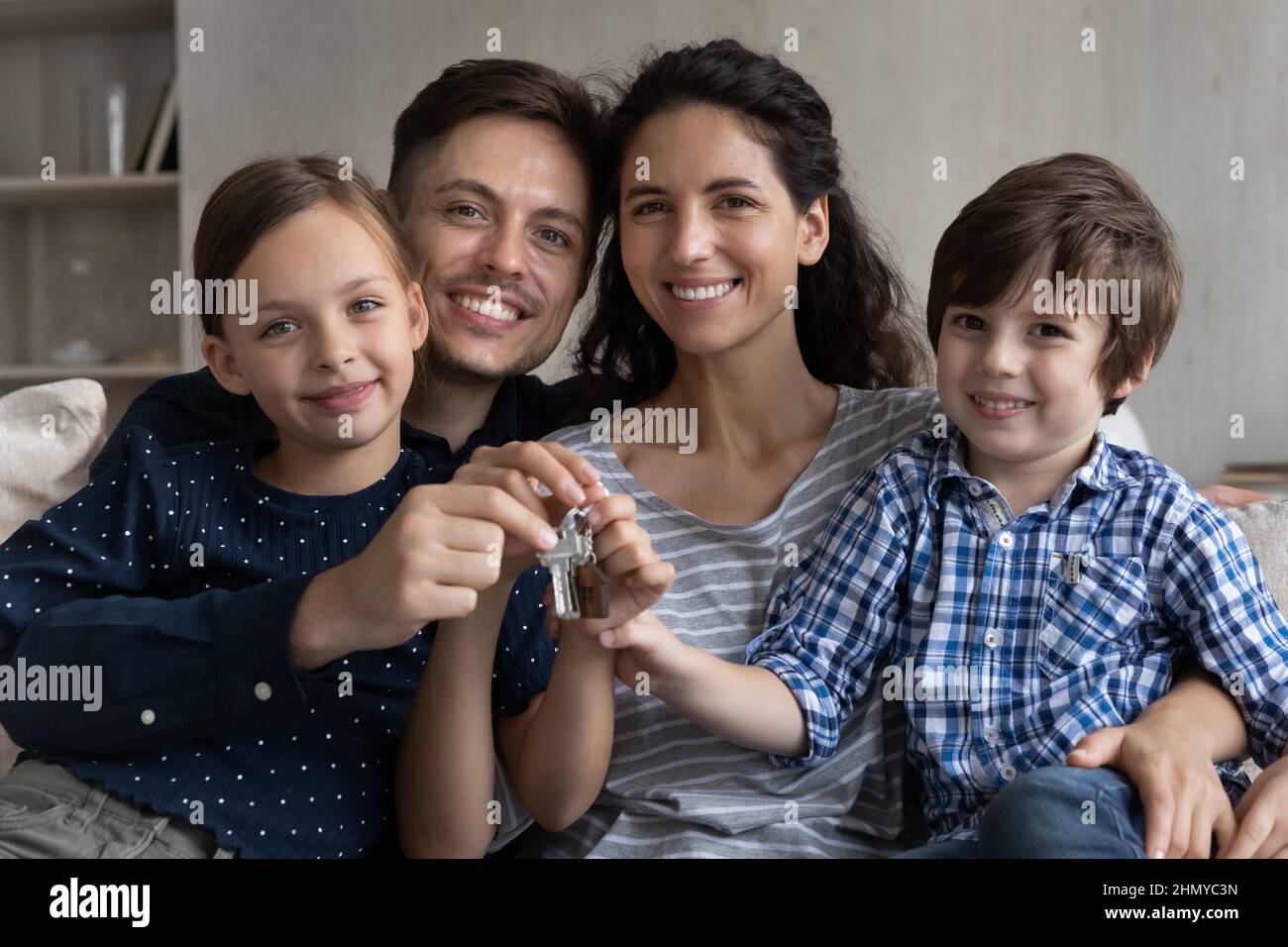 Couple heureux et deux enfants tenant les clés de la nouvelle maison Banque D'Images