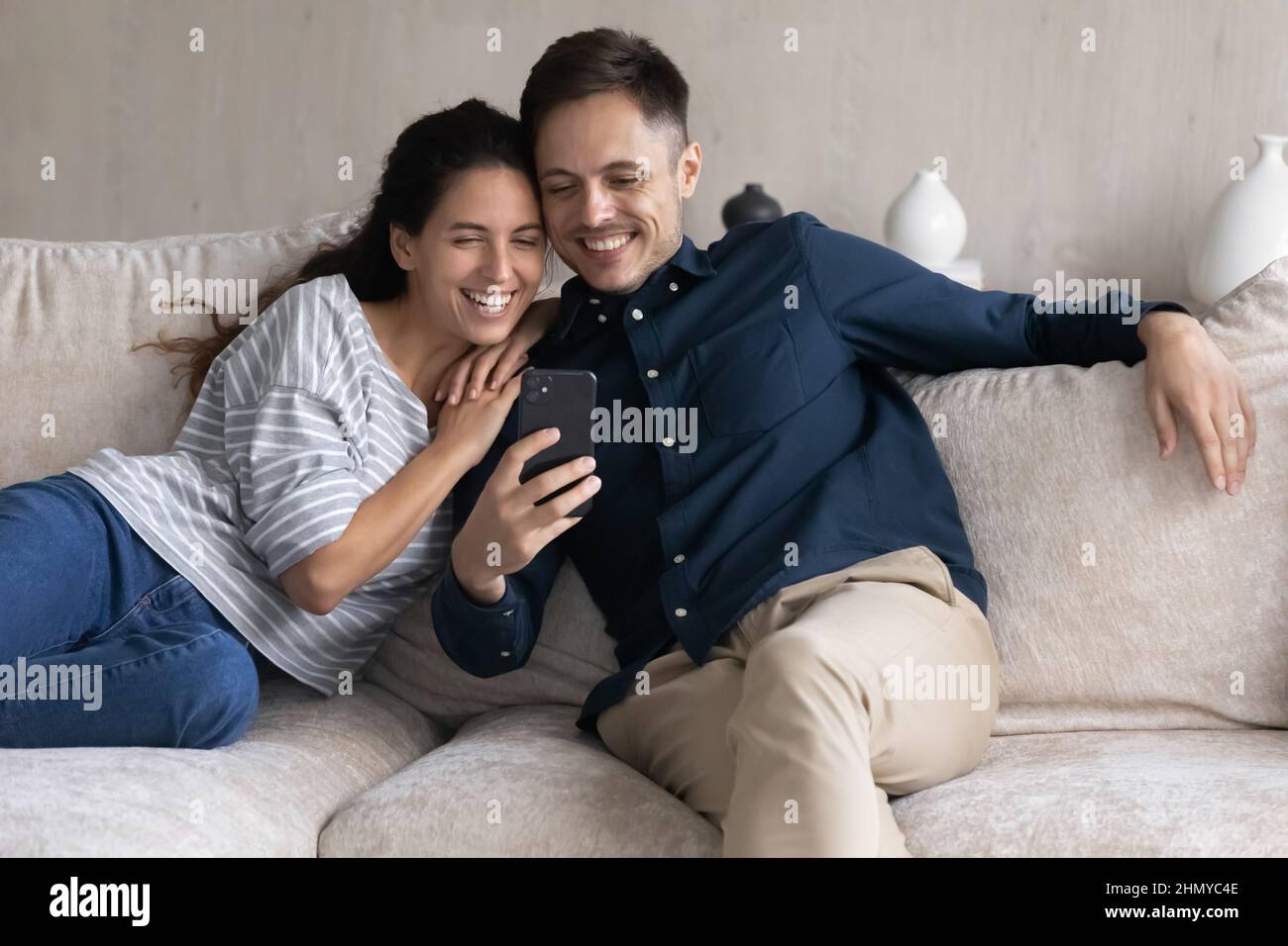 Joyeux jeune couple joyeux regardant du contenu multimédia amusant sur smartphone Banque D'Images