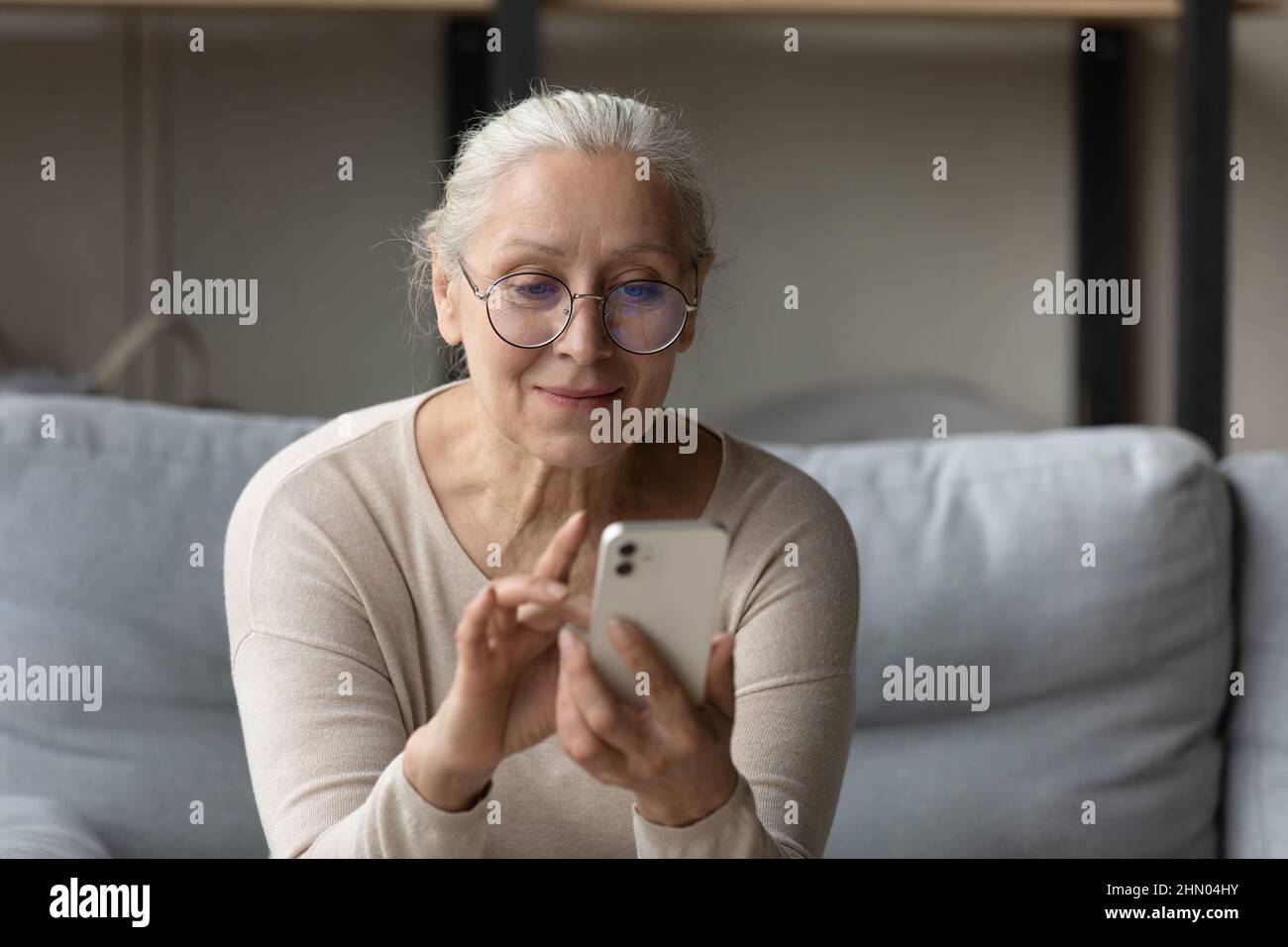 Bonne femme âgée en lunettes lisant un message texte Banque D'Images