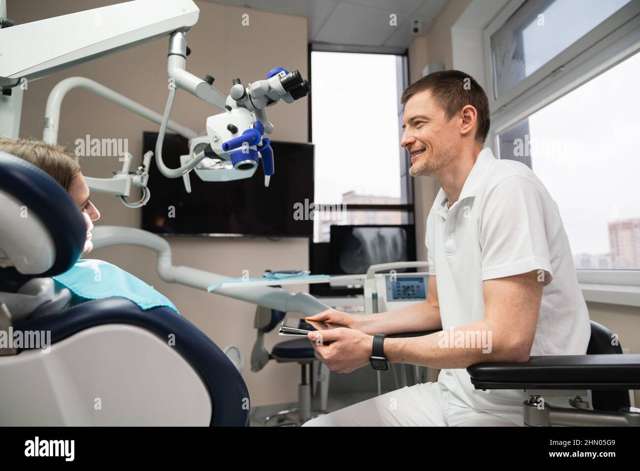 Le dentiste communique avec le patient au cabinet dentaire à l'aide d'une tablette numérique Banque D'Images