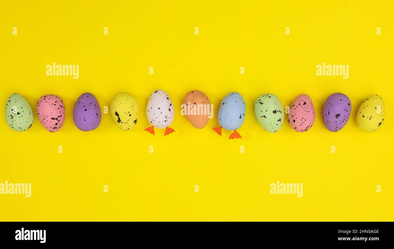 Motif Pâques créatif coloré avec œufs sur fond jaune vif. Concept de ressort de pose plate. Banque D'Images