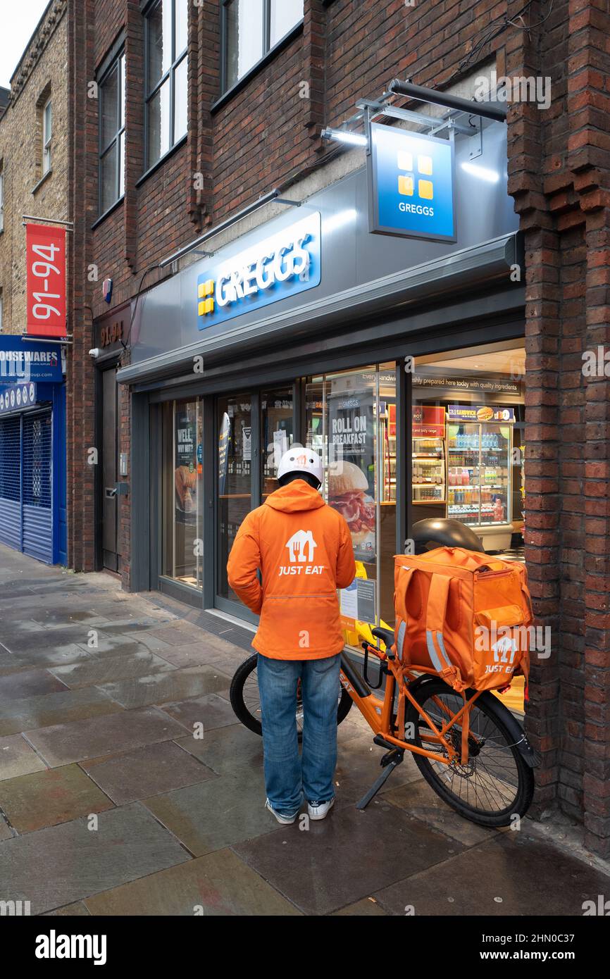 Un livreon de juste manger est prêt à entrer Greggs pour récupérer une commande pour la livraison. Pris tôt le dimanche matin à Lower Marsh, Waterloo, Londres Banque D'Images