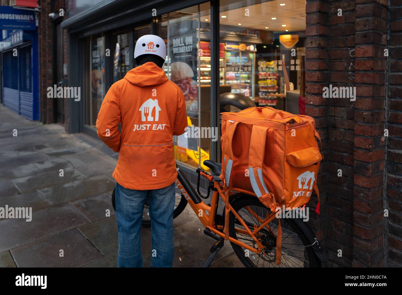 Un livreon de juste manger est prêt à entrer Greggs pour récupérer une commande pour la livraison. Pris tôt le dimanche matin à Lower Marsh, Waterloo, Londres Banque D'Images