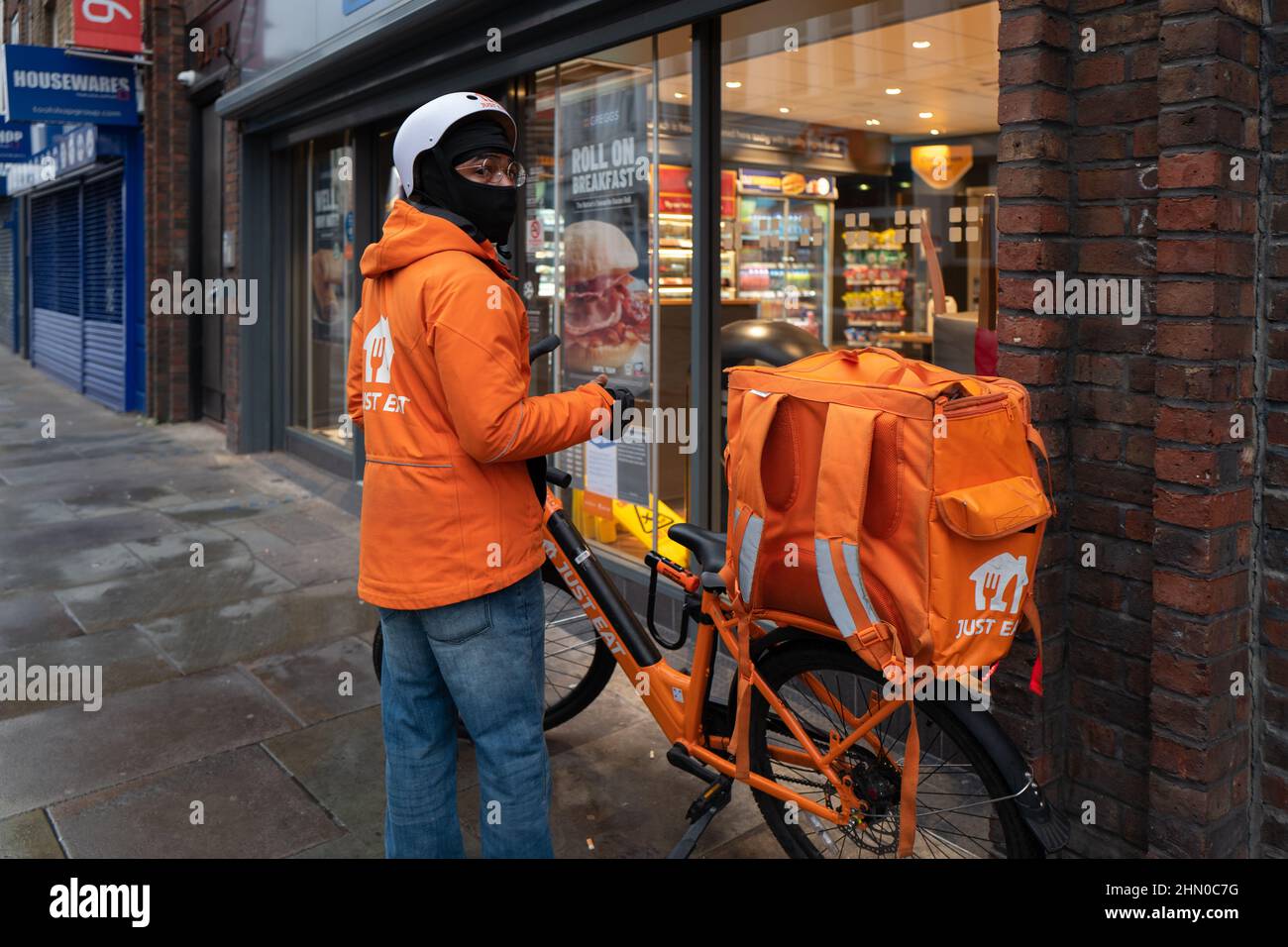 Un livreon de juste manger est prêt à entrer Greggs pour récupérer une commande pour la livraison. Pris tôt le dimanche matin à Lower Marsh, Waterloo, Londres Banque D'Images