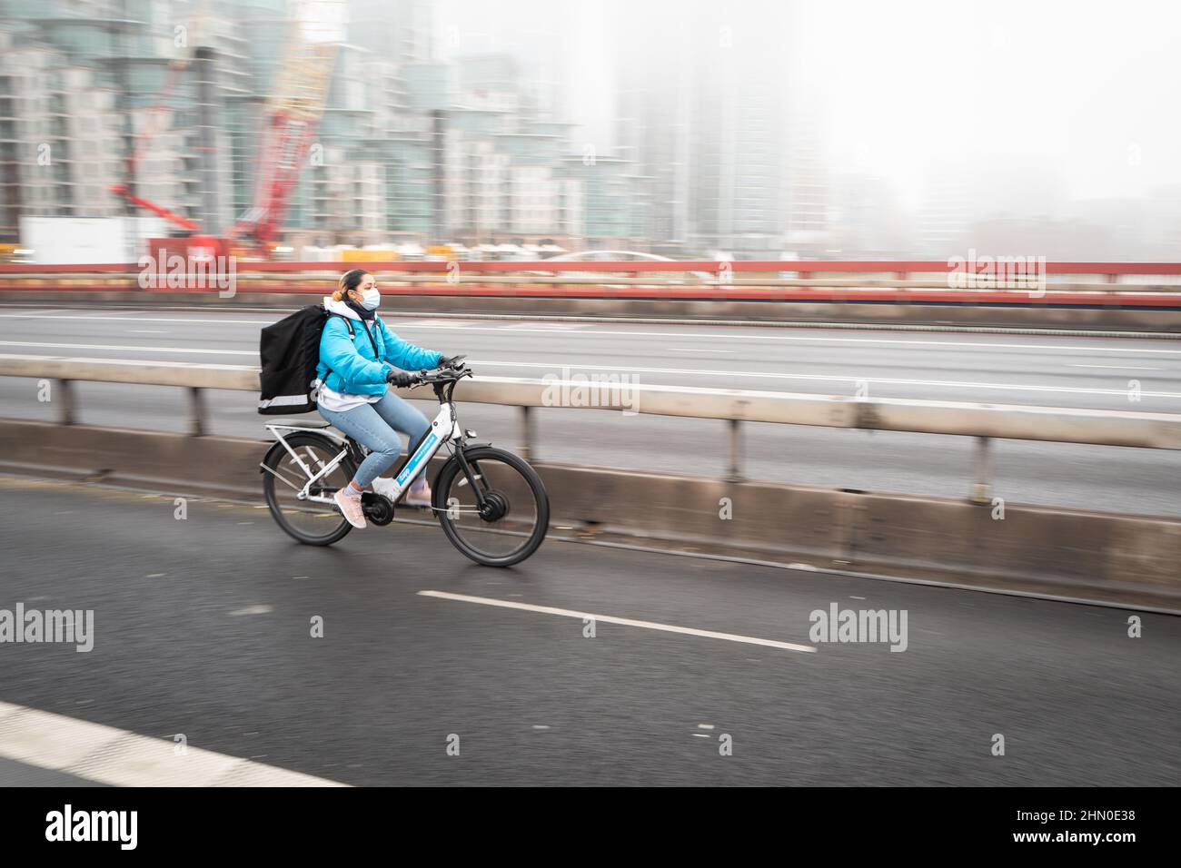 Un cycliste traverse le pont Vauxhall dans un matin d'hiver humide et brumeux à Londres, au Royaume-Uni. Banque D'Images