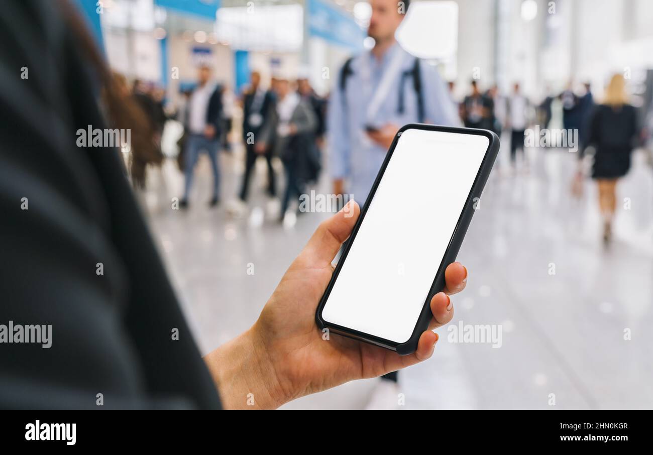 vue du téléphone dans les mains des femmes avec écran vide, avec foule de personnes, espace de copie pour votre texte individuel. Banque D'Images