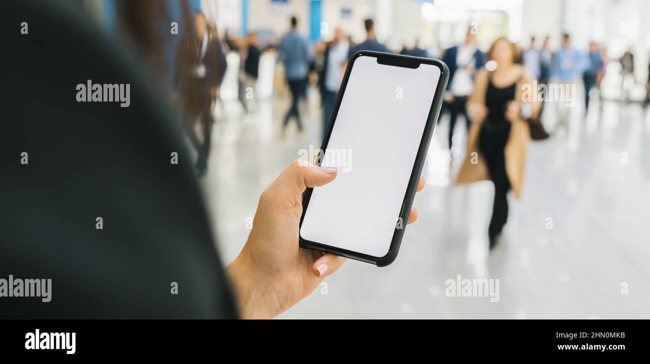 Femme main tenant téléphone portable noir avec écran blanc à un salon, espace de copie pour votre texte individuel. Banque D'Images