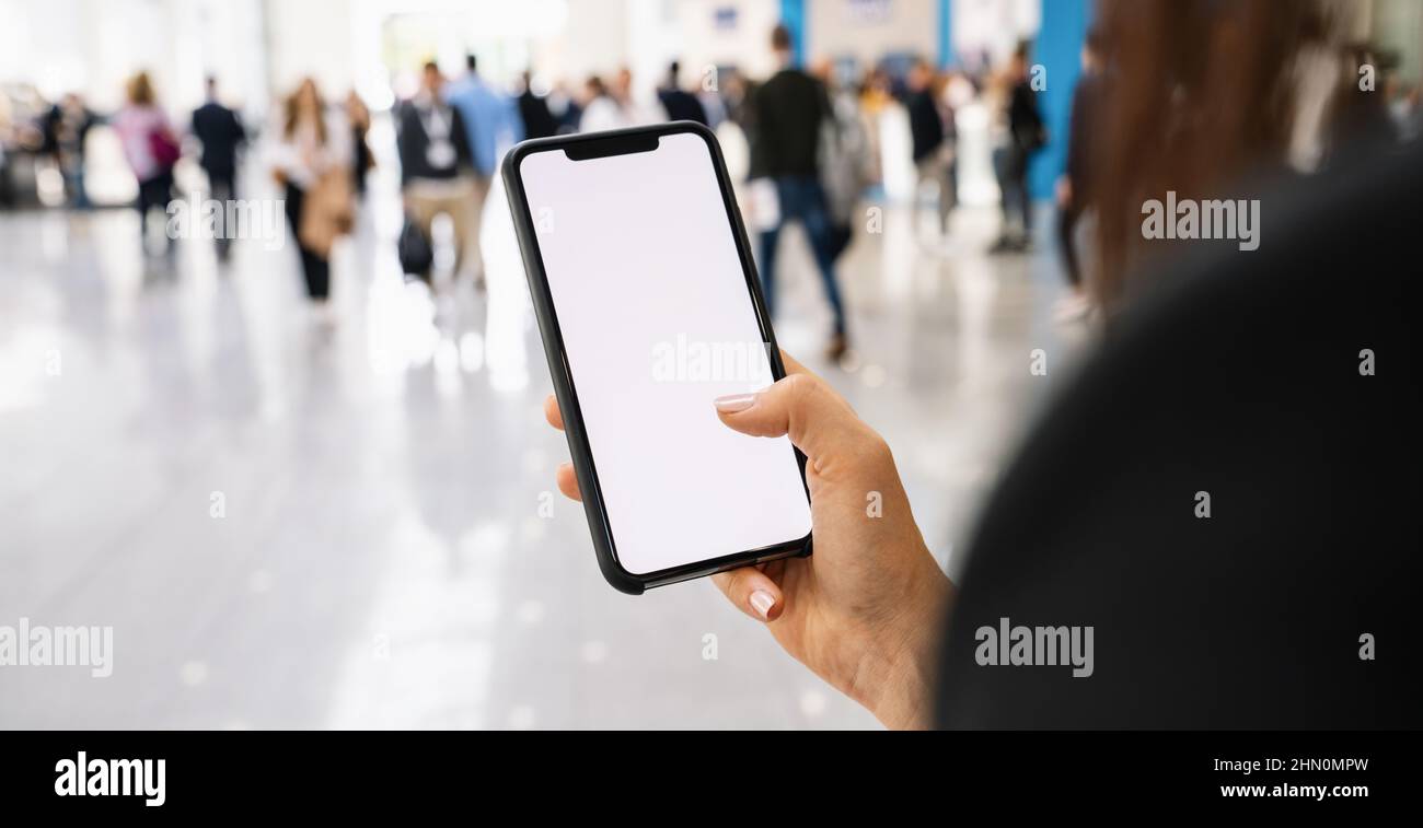 Femme d'affaires main tenant téléphone portable noir avec écran blanc à un salon, espace de copie pour votre texte individuel. Banque D'Images