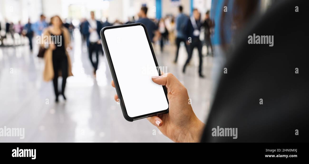 Femme d'affaires main tenant téléphone portable noir avec écran blanc à un salon, espace de copie pour votre texte individuel. Banque D'Images