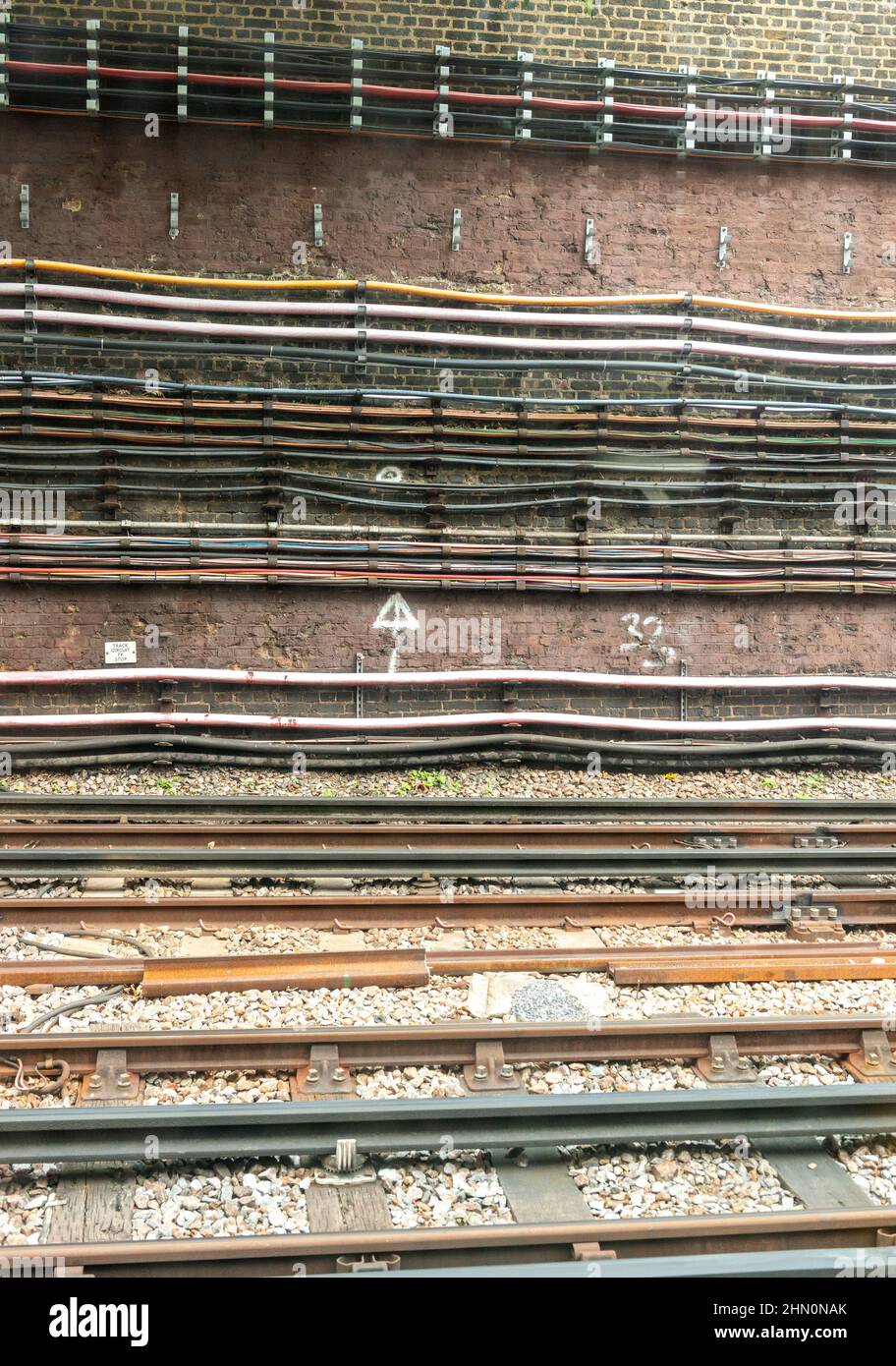 Câbles fixés à un mur du métro londonien avec rail au premier plan Banque D'Images