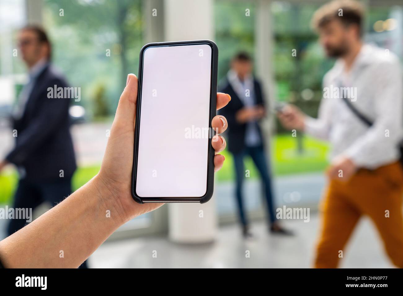 Femme main tenant téléphone portable noir avec écran blanc à un salon, espace de copie pour votre texte individuel. Banque D'Images