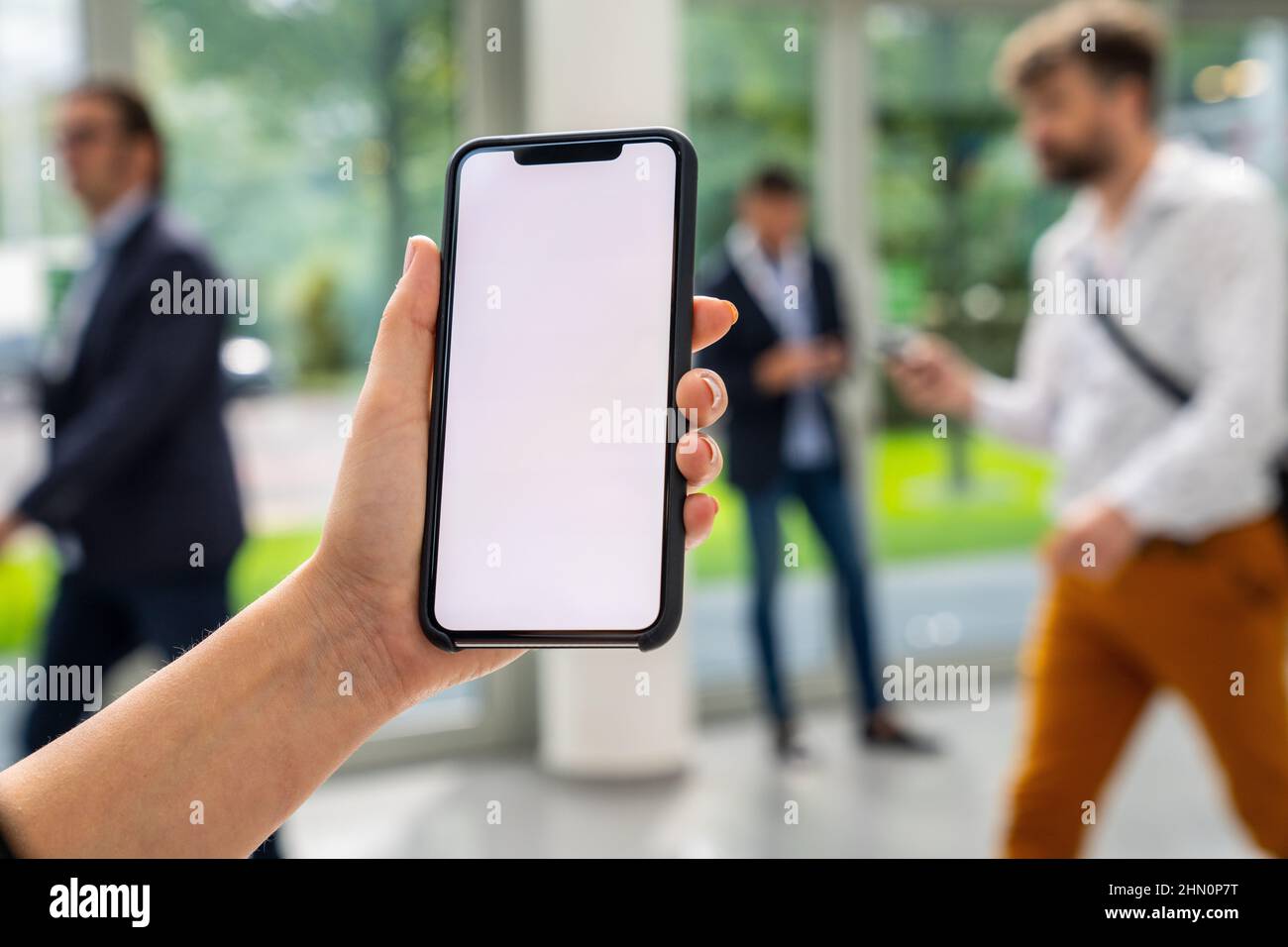 Femme d'affaires main tenant téléphone portable noir avec écran blanc à un salon, espace de copie pour votre texte individuel. Banque D'Images