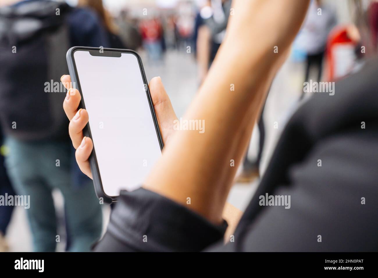 Femme d'affaires main tenant téléphone portable noir avec écran blanc à un salon, espace de copie pour votre texte individuel. Banque D'Images