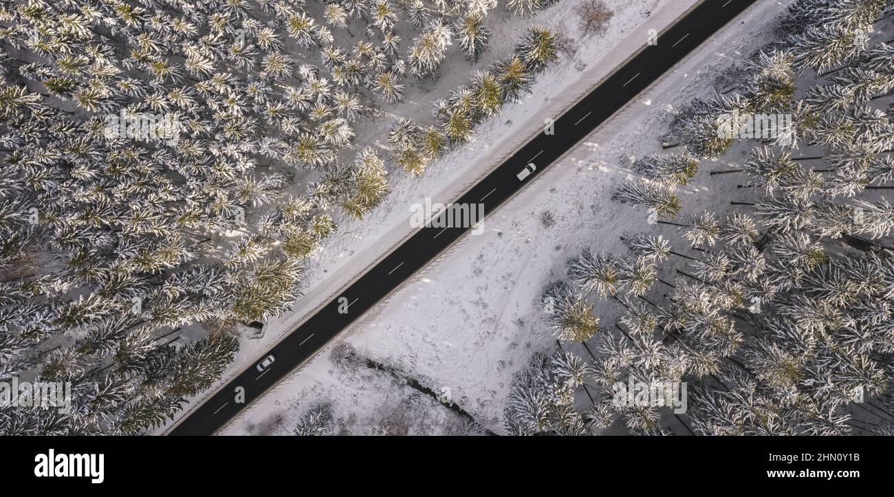 Vue aérienne de la forêt enneigée avec une route et une voiture. Capturé par le dessus avec un drone Banque D'Images