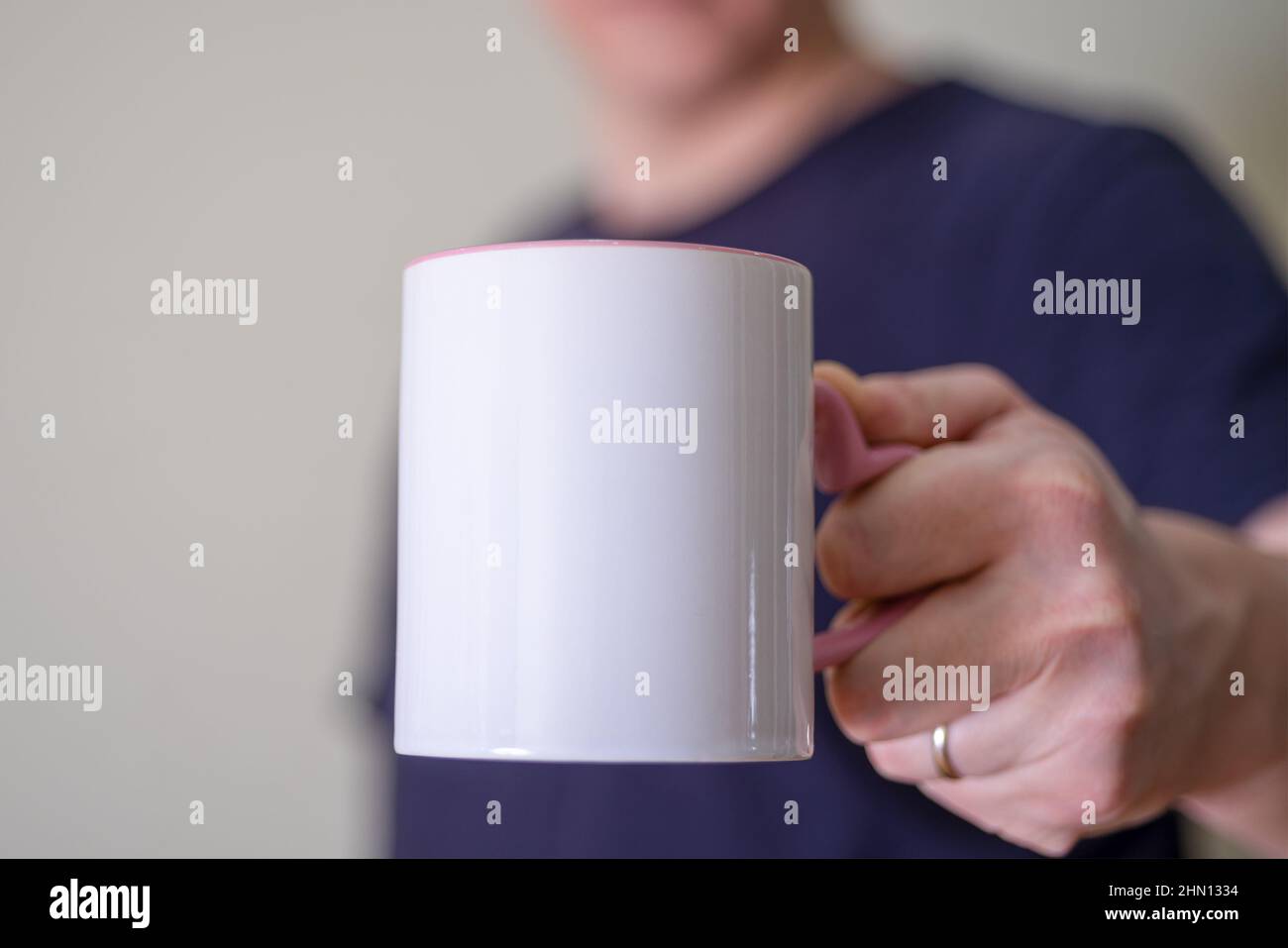 Homme tenant une tasse blanche de boisson chaude à l'extérieur. Main de l'homme tenant une tasse vierge sur fond noir. Gros plan, maquette d'image, espace de copie pour le texte Banque D'Images