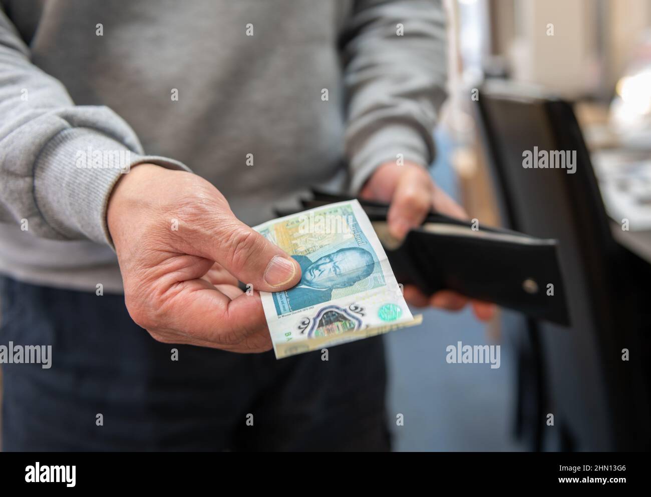 Un client payant avec un billet de banque dans un magasin. Inflation, concept du coût de la vie. Banque D'Images