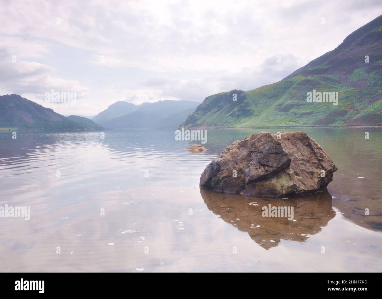 Vue sur le lac Ennerdale dans le quartier des lacs, Royaume-Uni avec ciel couvert et roche en premier plan. Banque D'Images