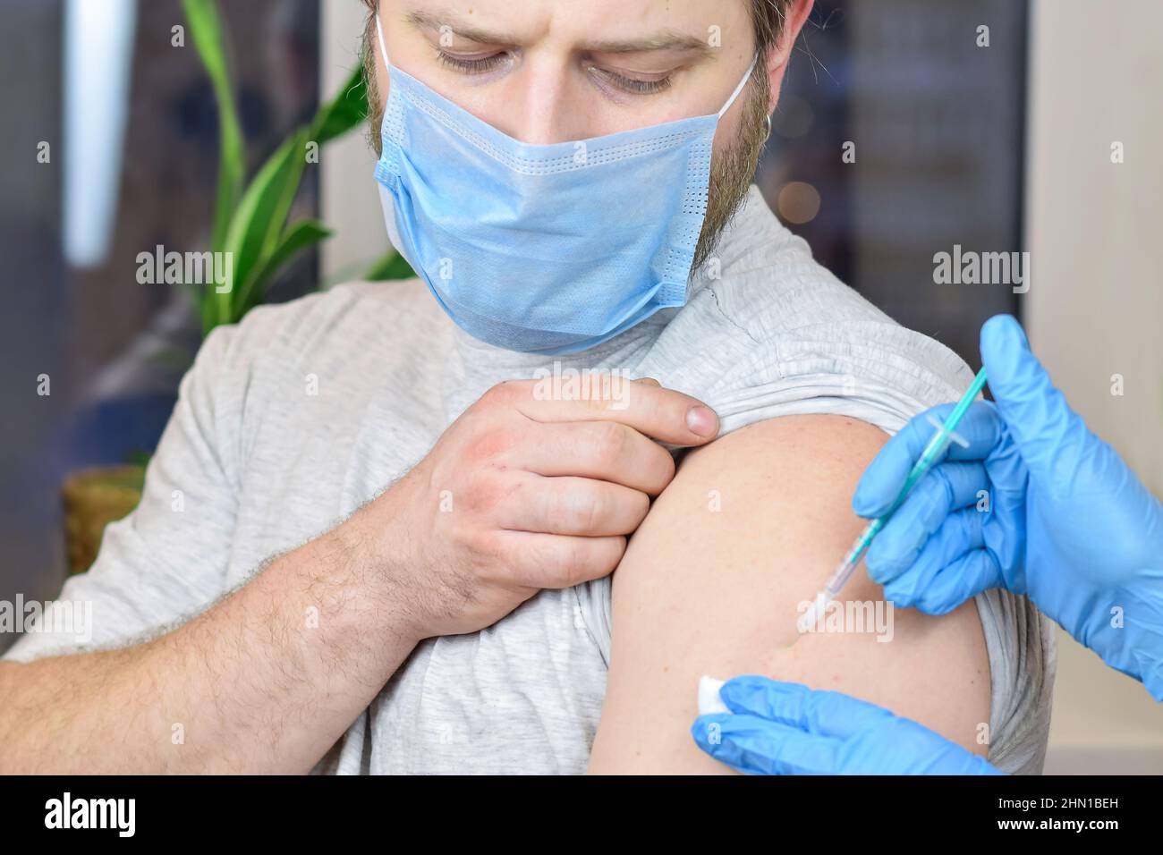 Mains du médecin injectant le vaccin contre le coronavirus covid-19 dans une seringue de vaccin dans le muscle du bras de l'homme caucasien pour l'immunisation contre le covid. Banque D'Images