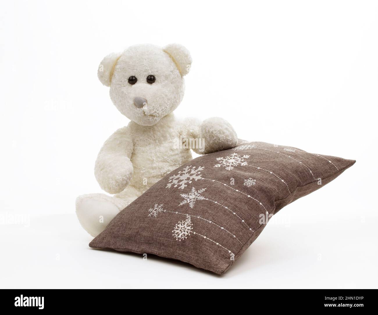 Ours en peluche blanc avec coussin brun brodé de flocons de neige isolés sur du blanc Banque D'Images