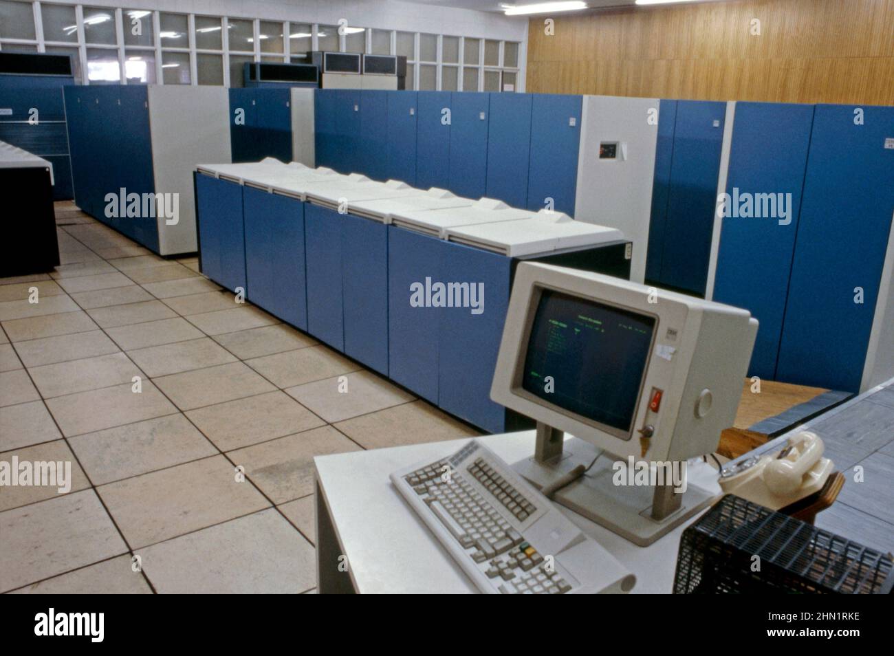 Une vue à la mi-1980s à l'intérieur des aciéries de Port Talbot, une usine intégrée de production d'acier à Port Talbot, West Glamourgan, pays de Galles, Royaume-Uni. Il s'agit d'une vue de la salle informatique de l'entreprise. Les gros ordinateurs commençaient à jouer un rôle important dans l'industrie à ce moment-là. Un écran et un clavier IBM sont au premier plan. Les PC portables et les tablettes disposent désormais de la puissance et de la vitesse de calcul nécessaires pour prendre le relais des machines anciennes, de taille importante et défunte. Cette image est tirée d'une transparence de couleur vintage – une photographie vintage 1980s. Banque D'Images