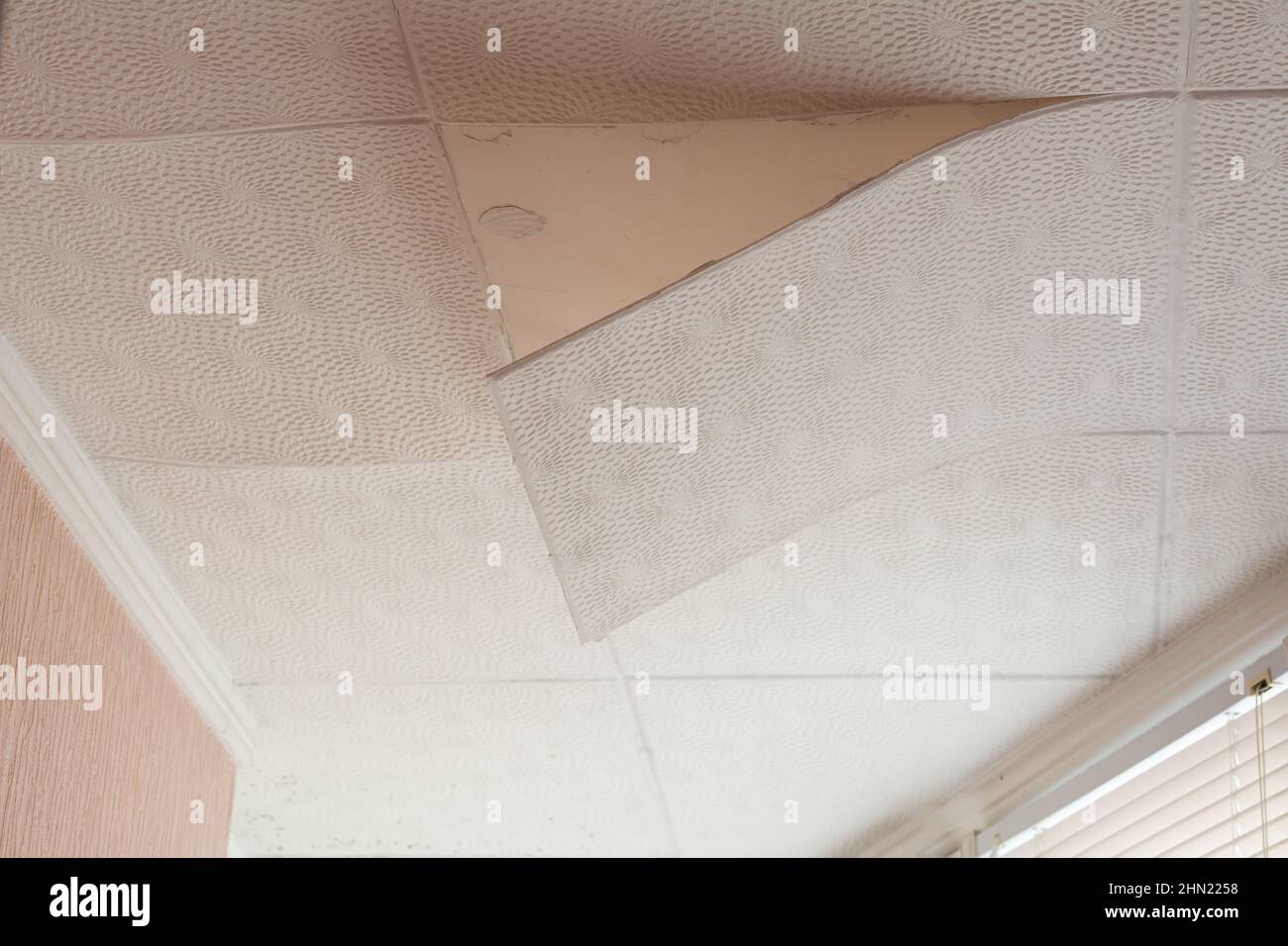 Les carreaux de plafond ont décollé du plafond. Carreaux de plafond de mauvaise qualité. Carreaux de plafond en pvc endommagés. Mauvaise réparation du plafond. Banque D'Images