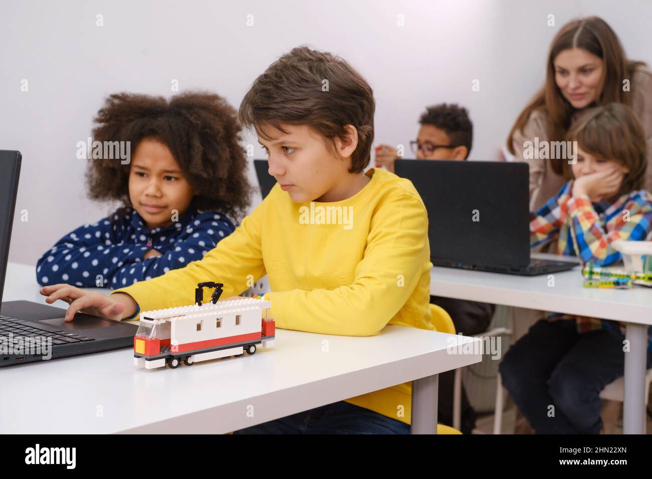 Les enfants apprennent le codage, la science et la technologie en classe scolaire. Des enfants afro-américains et caucasiens ont été cloués avec des ordinateurs portables dans la LEÇON STEM Banque D'Images