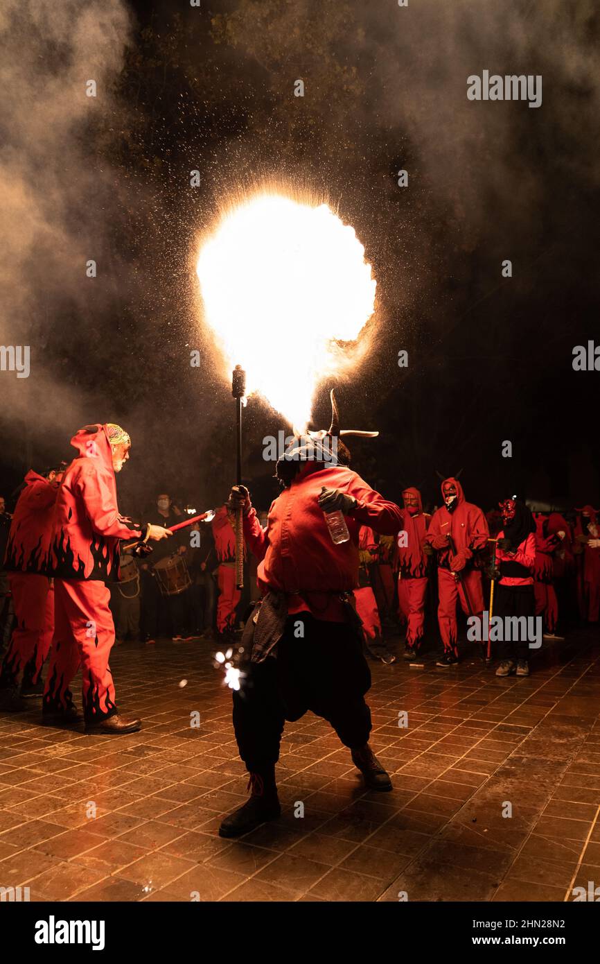 Valence, Espagne - 11 février 2022 : un homme habillé comme un démon craquant le feu dans sa bouche parmi un groupe de 'dimonis' pendant la fête traditionnelle espagnole Banque D'Images