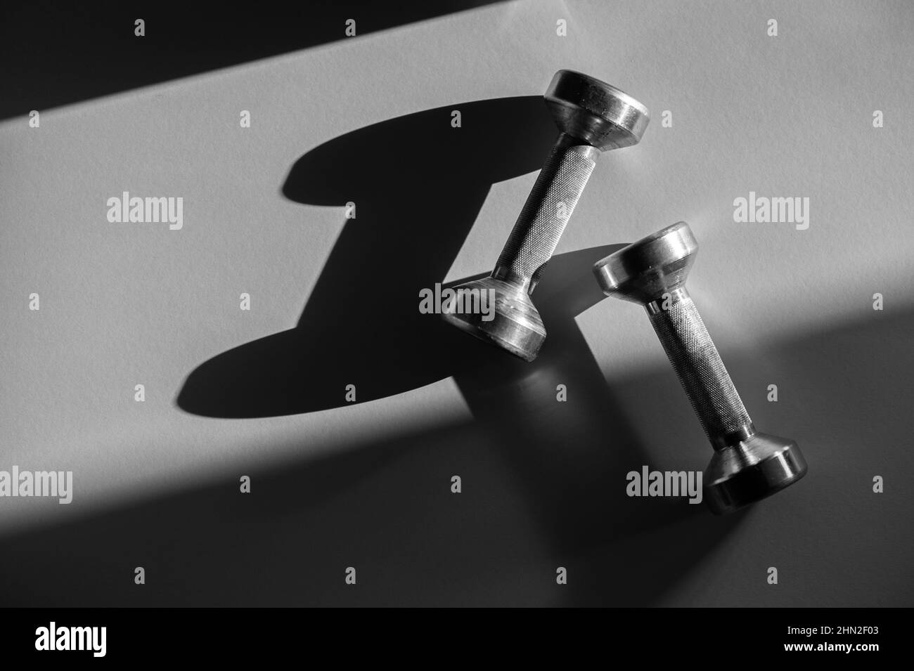 Haltères grises pour l'entraînement physique sur fond sombre. Concept de lumière naturelle. Affiche sport horizontale, cartes de vœux, en-têtes, site Web. Banque D'Images