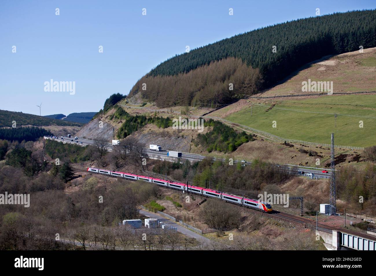 Virgin trains Alstom Pendolino train inclinable 390005 dans la campagne écossaise sur la ligne principale électrifiée de la côte ouest, par l'autoroute A74(M) Banque D'Images