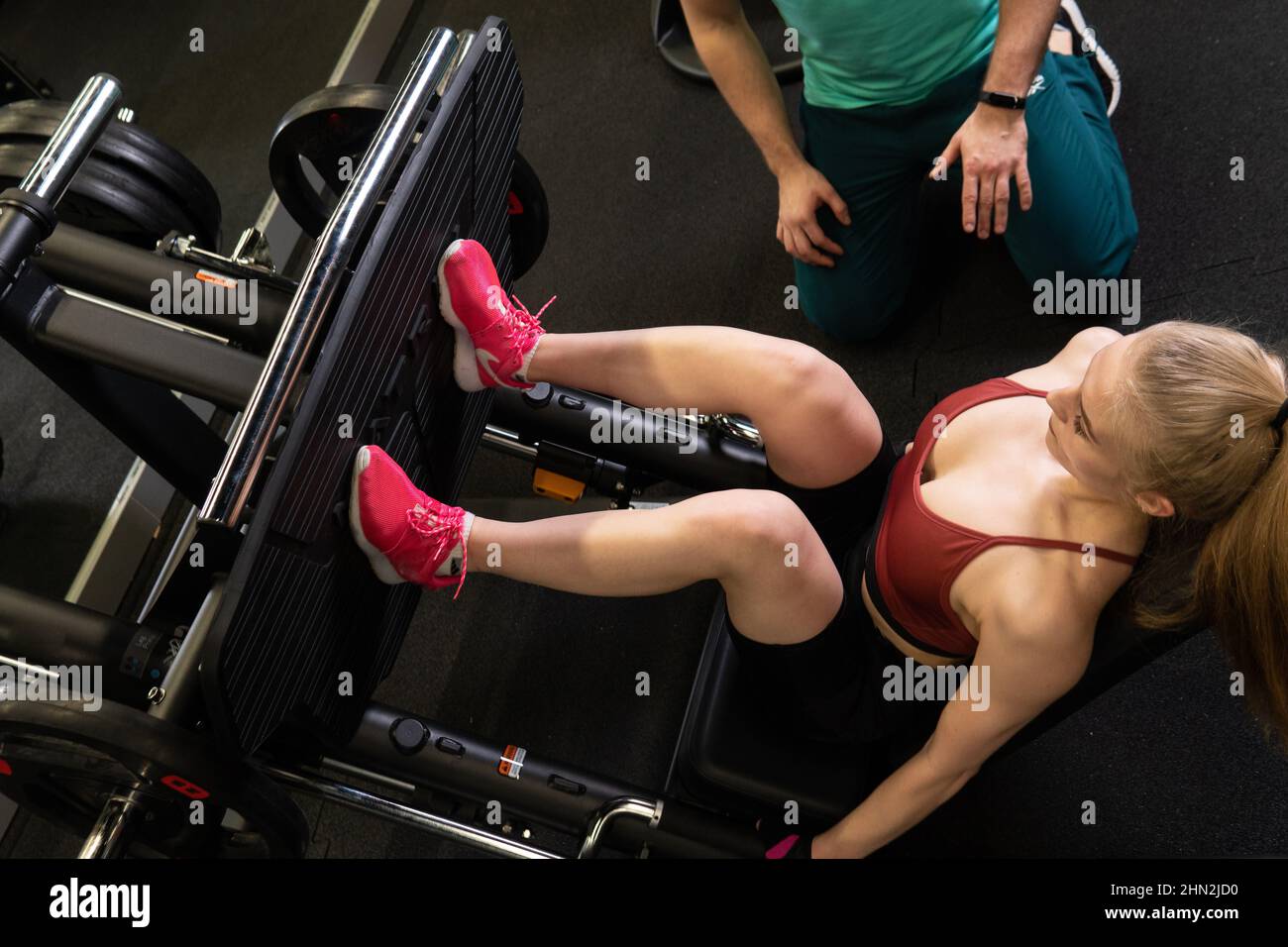 L'entraînement dirigé par un instructeur aide un beau client à effectuer des exercices dans un club de remise en forme, le concept de jouer du sport avec un loisir professionnel de gym Banque D'Images