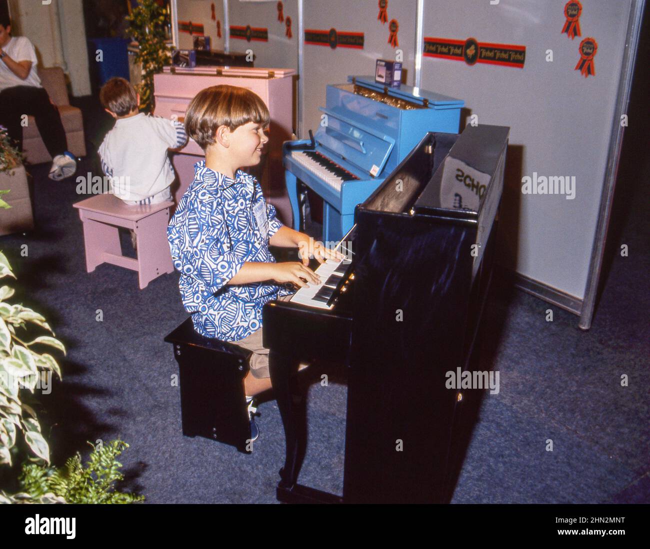 Très jeune garçon essayant un mini piano à la British Music Fair, Londres, en 1990s. Banque D'Images