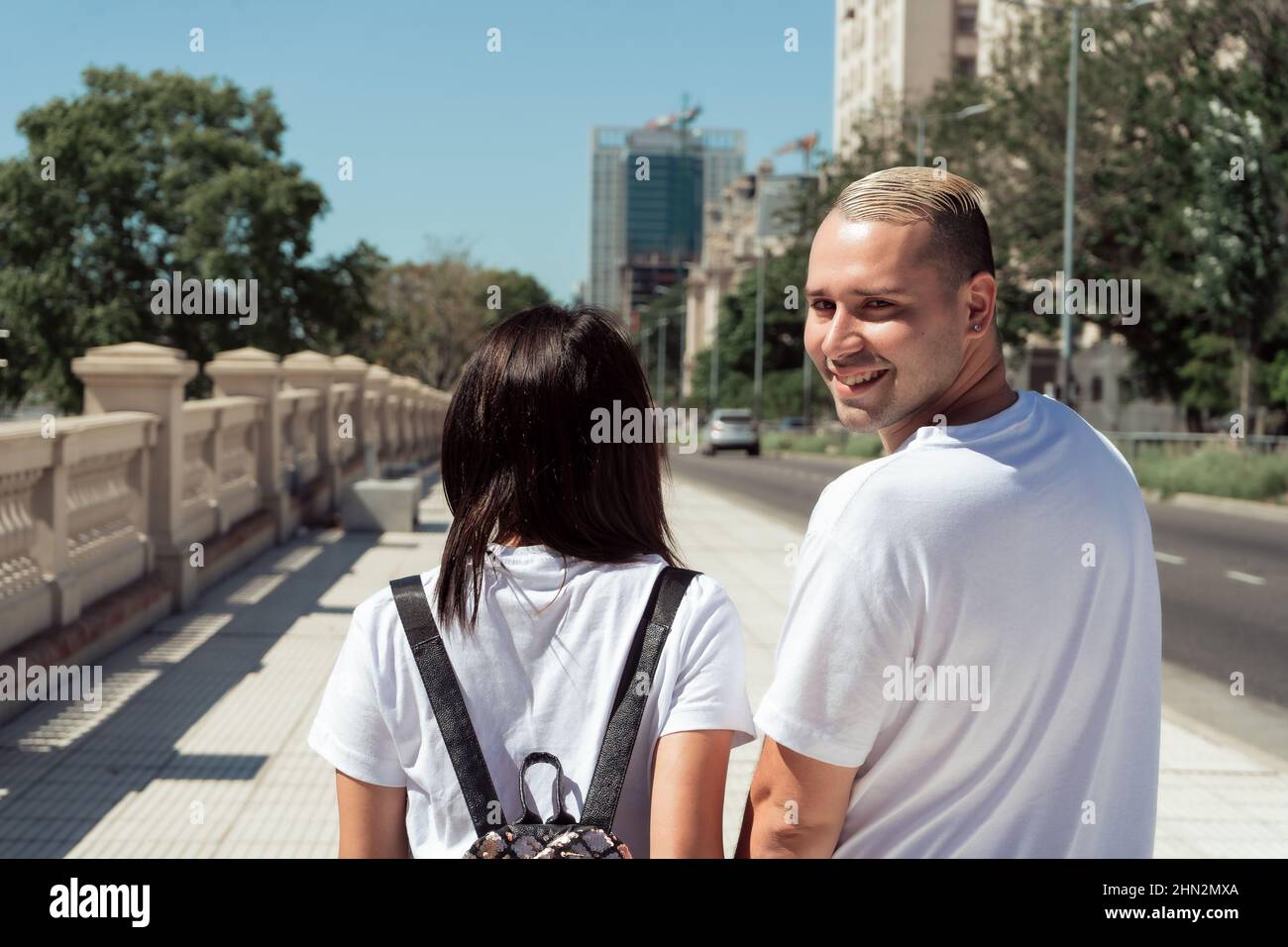 Un portrait d'un couple Latino marchant dans la rue et l'homme regardant en arrière souriant. Concept de bonheur, amour. Banque D'Images