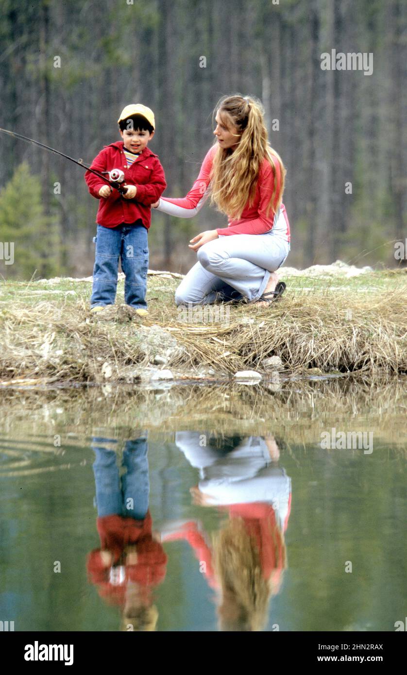 Mère enseignant au jeune fils comment pêcher dans un lac du Montana Banque D'Images